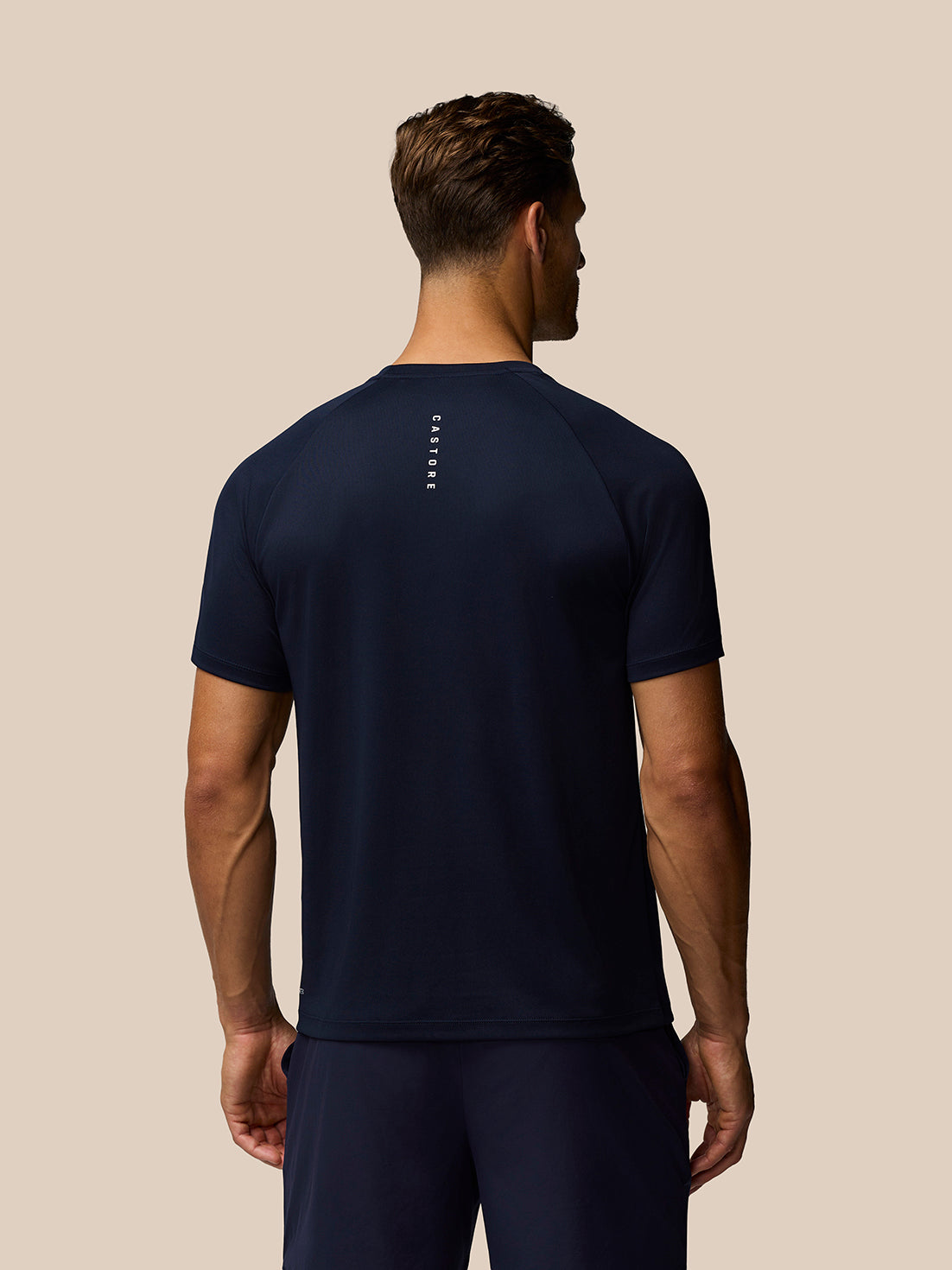 Back view of a male model in midnight navy Adapt Training T-Shirt with Castore branding along the upper back.