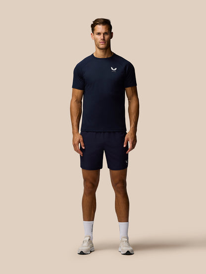 Front view of a male model wearing the midnight navy Adapt Training T-Shirt with Castore branding, paired with navy shorts.