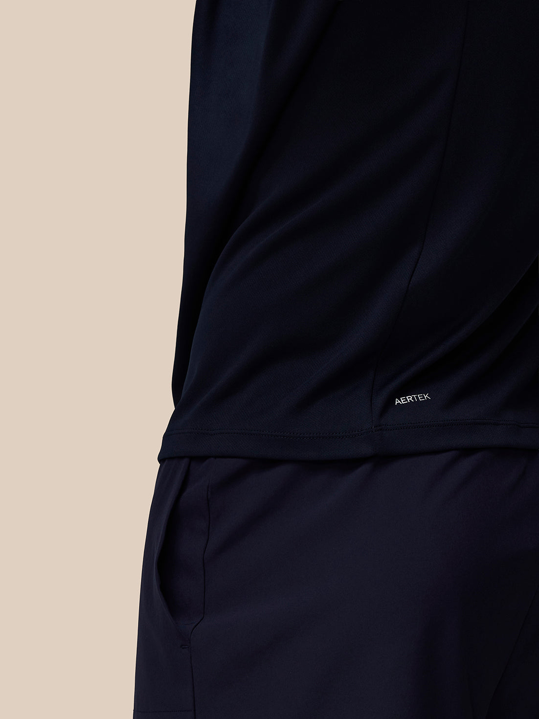 Close-up of the midnight navy Adapt Training T-Shirt hem showing AERTEK branding.