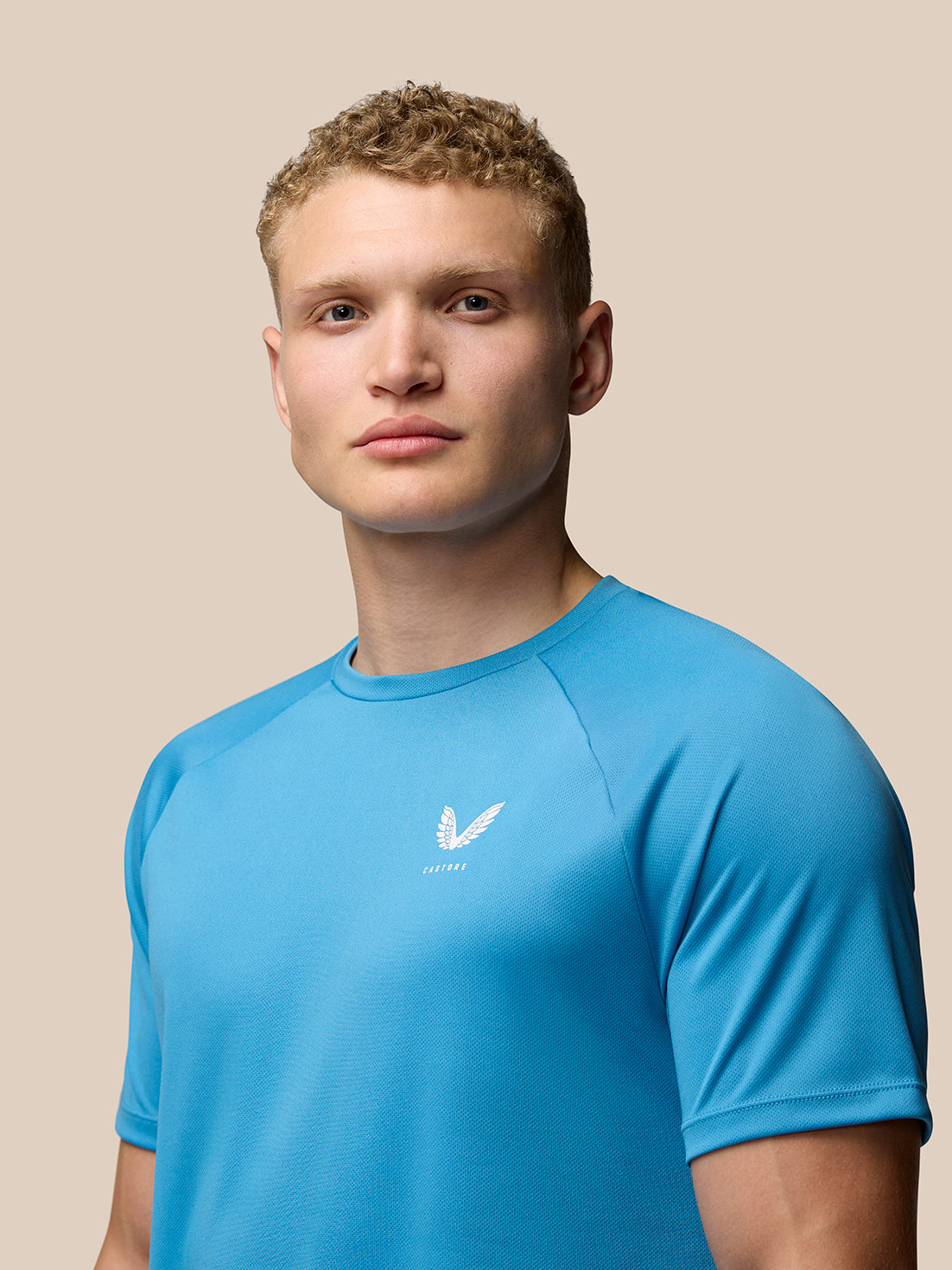 Model wearing corn blue Adapt Training T-Shirt front view showing Castore branding on left chest.