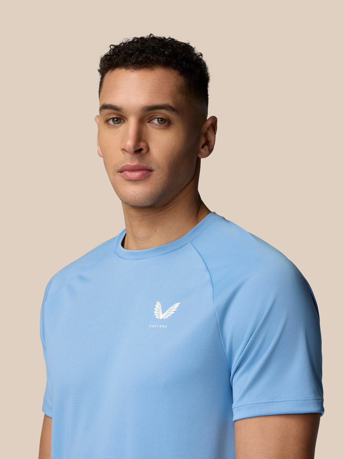 Three quarter view of male model in sky blue Adapt Training T-Shirt showing Castore logo on chest