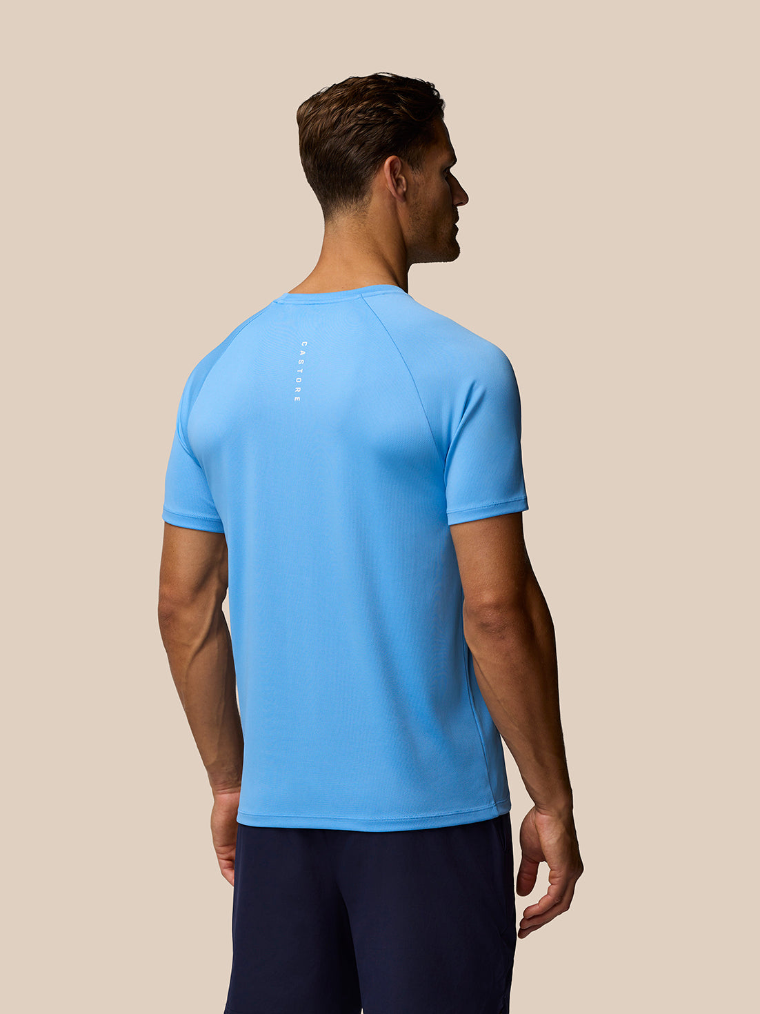 Back view of light blue Adapt Training T-Shirt on male model showing Castore branding along the upper back.