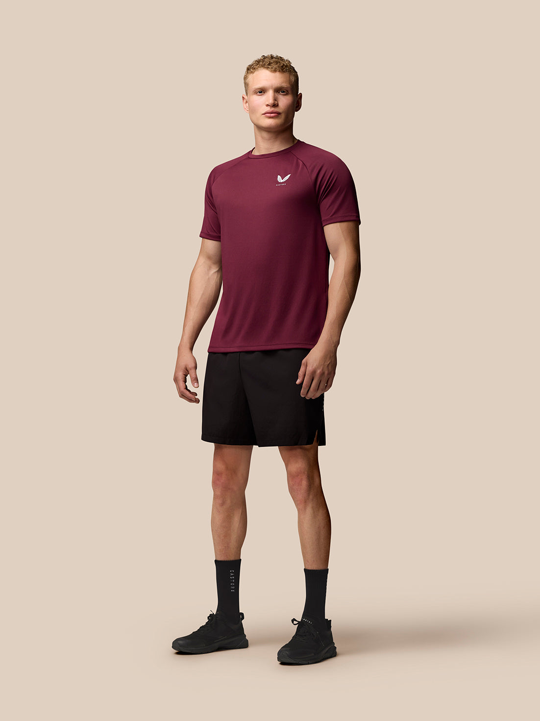 Male model wearing burgundy Adapt Training T Shirt with left chest Castore logo and AerTek branding on the back