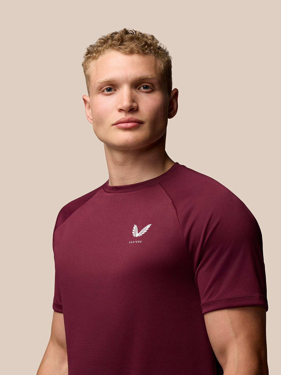 Man wearing burgundy Adapt Training T-Shirt showing Castore branding on left chest and upper back