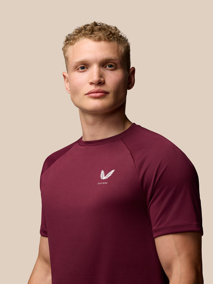 Man wearing burgundy Adapt Training T-Shirt showing Castore branding on left chest and upper back