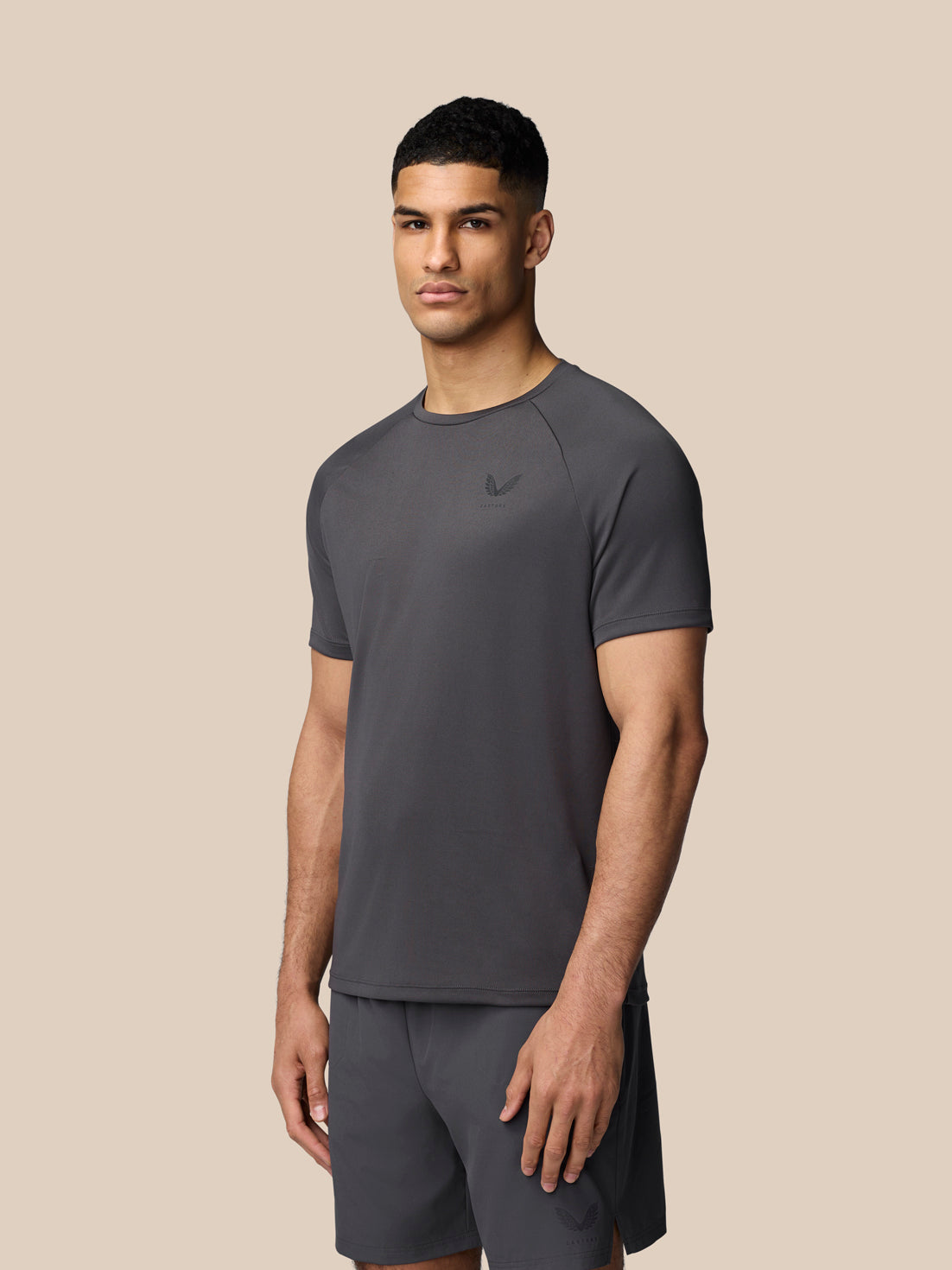 Male model wearing gunmetal Adapt Training T-Shirt with raglan sleeves and Castore branding on the chest