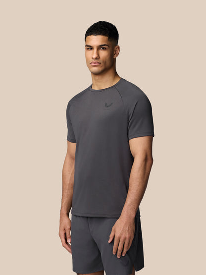 Male model wearing gunmetal Adapt Training T-Shirt with raglan sleeves and Castore branding on the chest