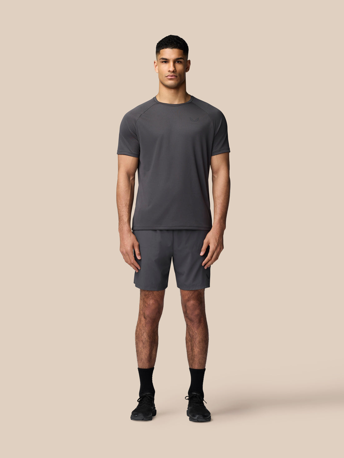 Full-body shot of male model wearing gunmetal Adapt Training T-Shirt with matching shorts against a neutral backdrop