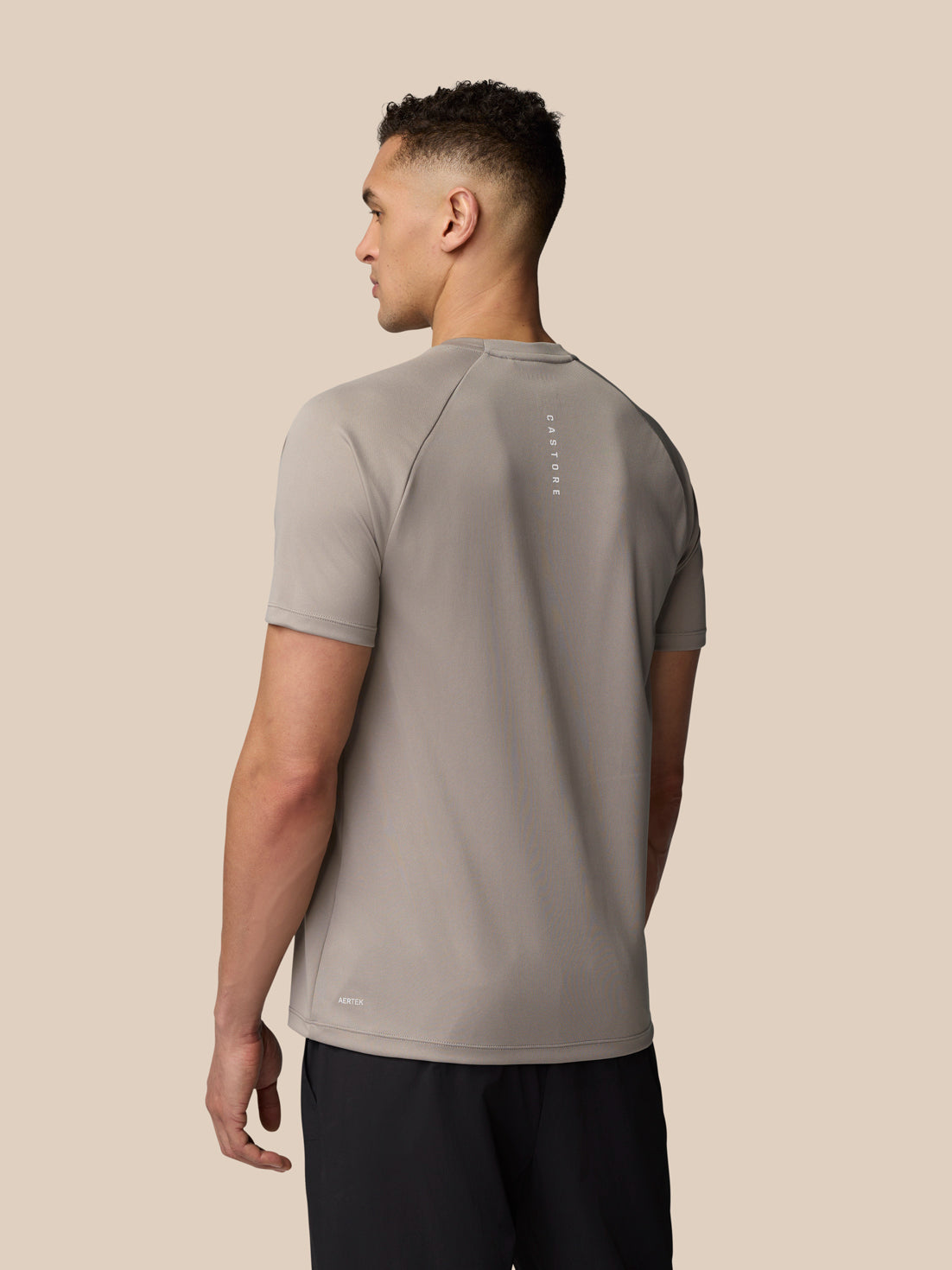 Back view of male model in light grey Adapt Training T-Shirt with vertical Castore branding along the upper back