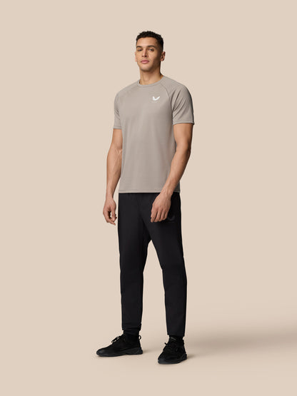 Male model wearing Rock Grey Adapt Training T-Shirt with crew neck raglan sleeves and Castore logo on the chest.