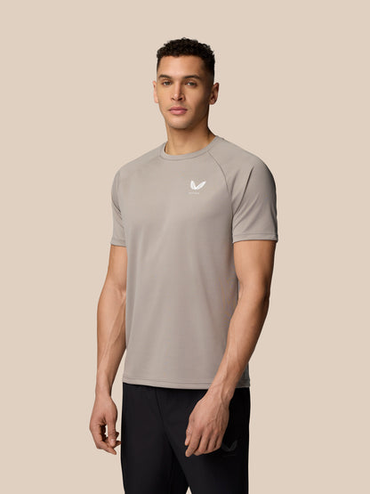 Male model wearing taupe Adapt Training T-Shirt with Castore logo on the chest against a beige backdrop