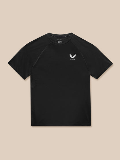 Flat lay of black Adapt Short Sleeve T Shirt with Castore logo on left chest against beige background