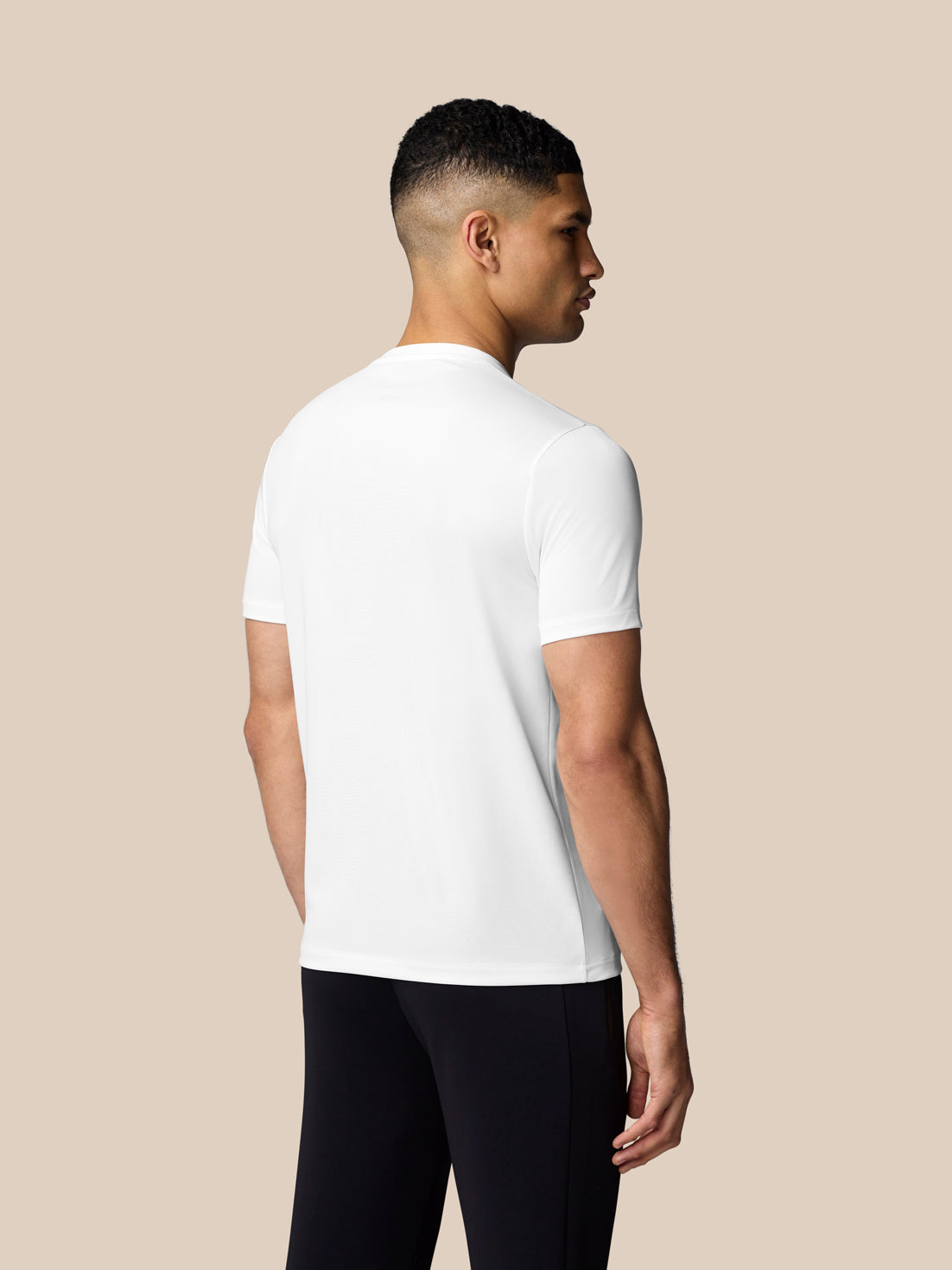 Back view of white graphic T shirt showing back branding at lower left area on male model