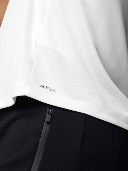 Close up of white training T-shirt hem showing Aertek branding with black pants zipper nearby