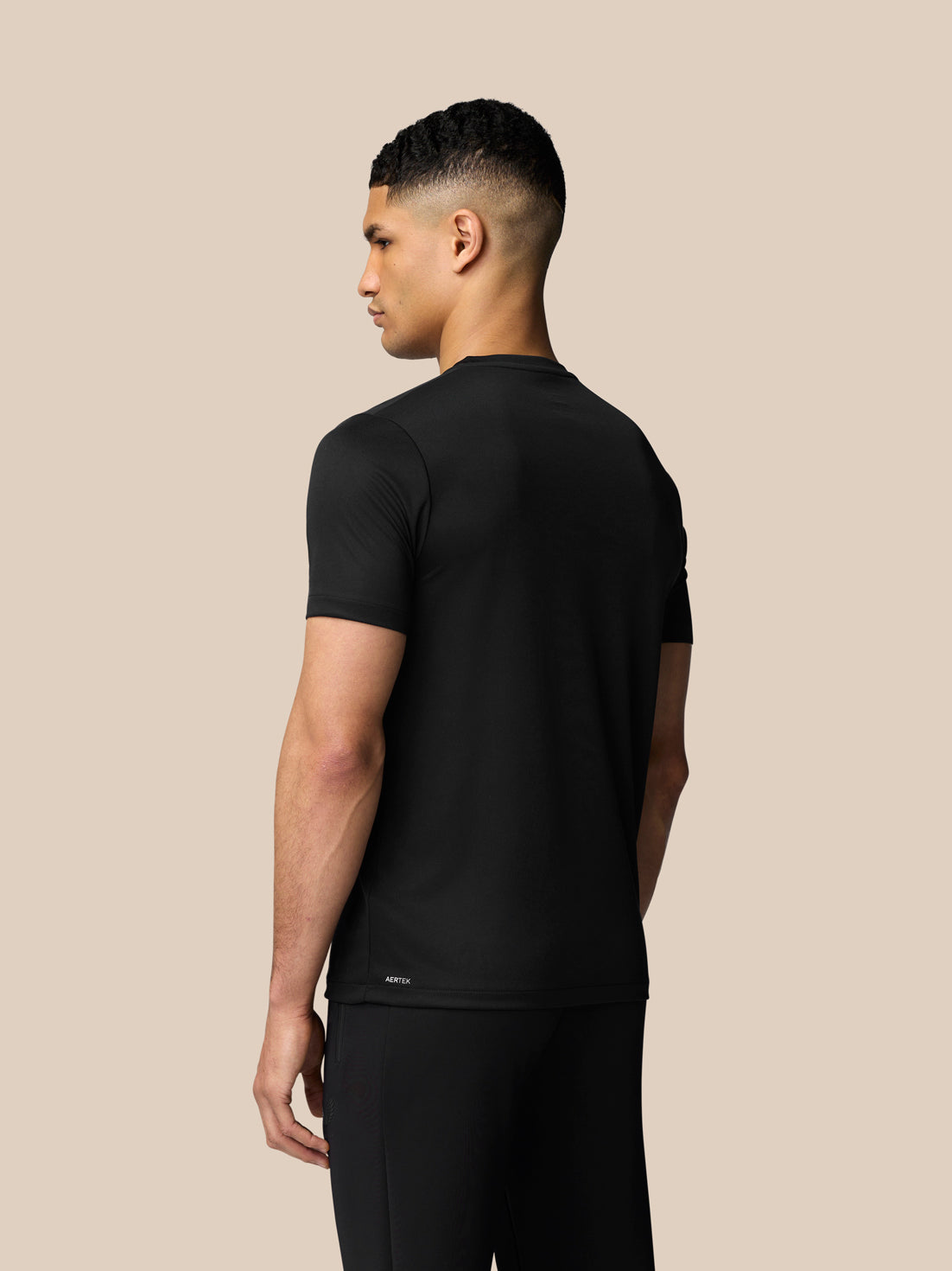 Back view of a man in a black graphic training T shirt with Aertek branding at the lower back