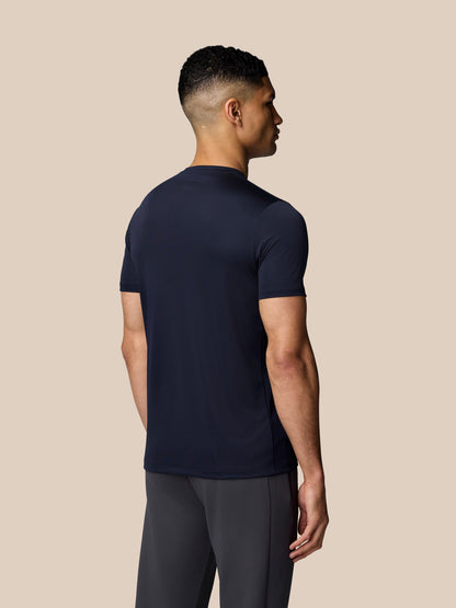 Close front view of male model wearing navy Castore graphic training T shirt with wing emblem.