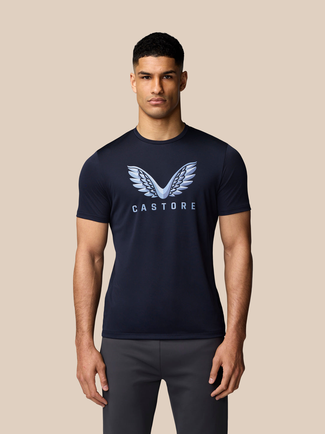 Male model in navy graphic training T shirt with Castore wings logo on chest.