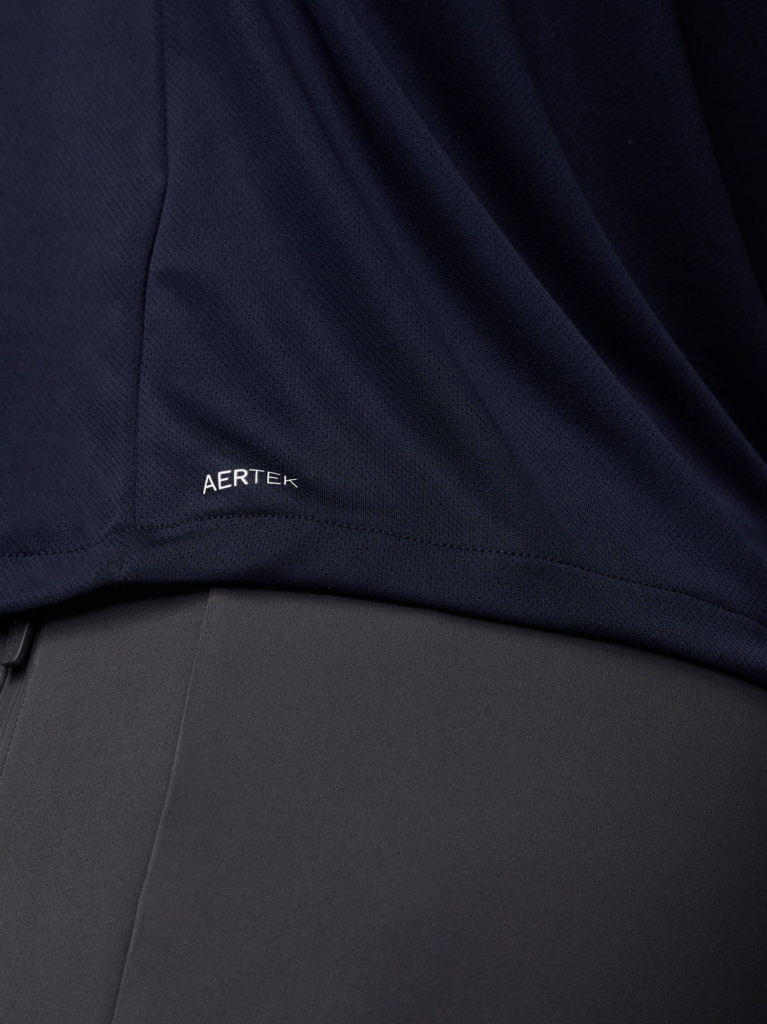 Close-up of navy mesh fabric with AERTEK branding at the hem