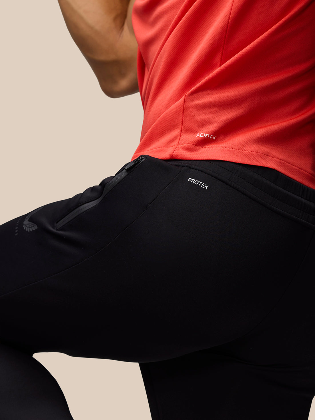 Side view of athlete in red graphic training T shirt and black Protek pants with AERTEK detail