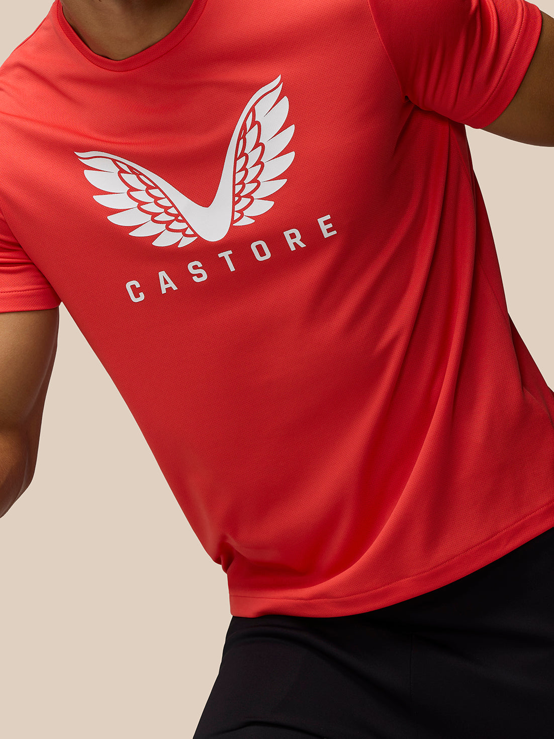 Close up of red graphic training T shirt showing white wing logo and Castore wordmark