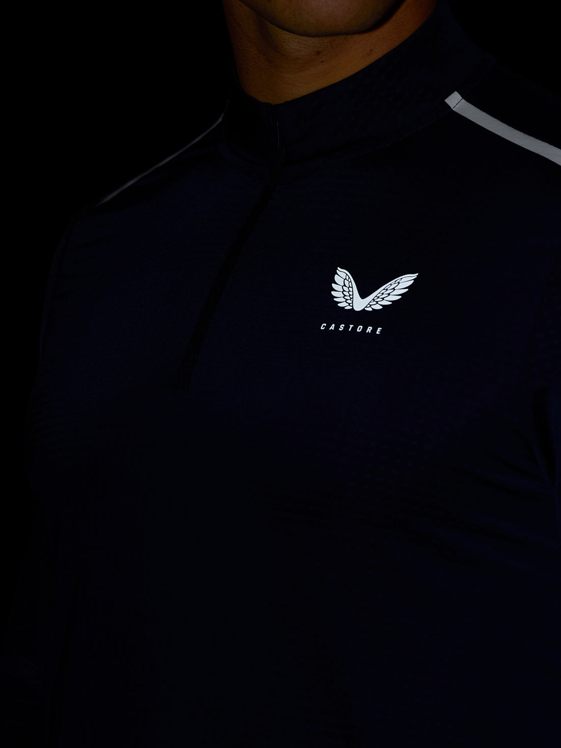 Close up of midnight navy Apex training top with quarter zip and Castore logo on chest.