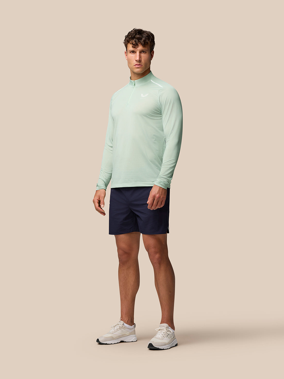 Full body shot of male model in mint Apex Aeromesh top paired with navy shorts and white sneakers