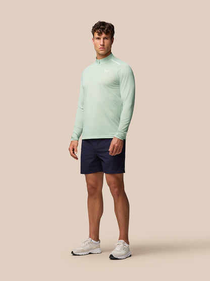 Full body shot of male model in mint Apex Aeromesh top paired with navy shorts and white sneakers