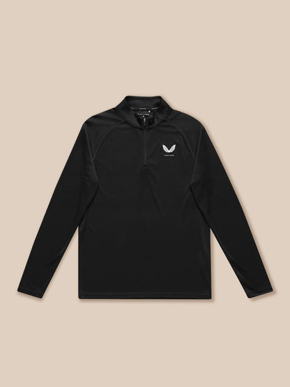 Black Adapt Training quarter zip top laid flat with left chest Castore logo on a tan backdrop