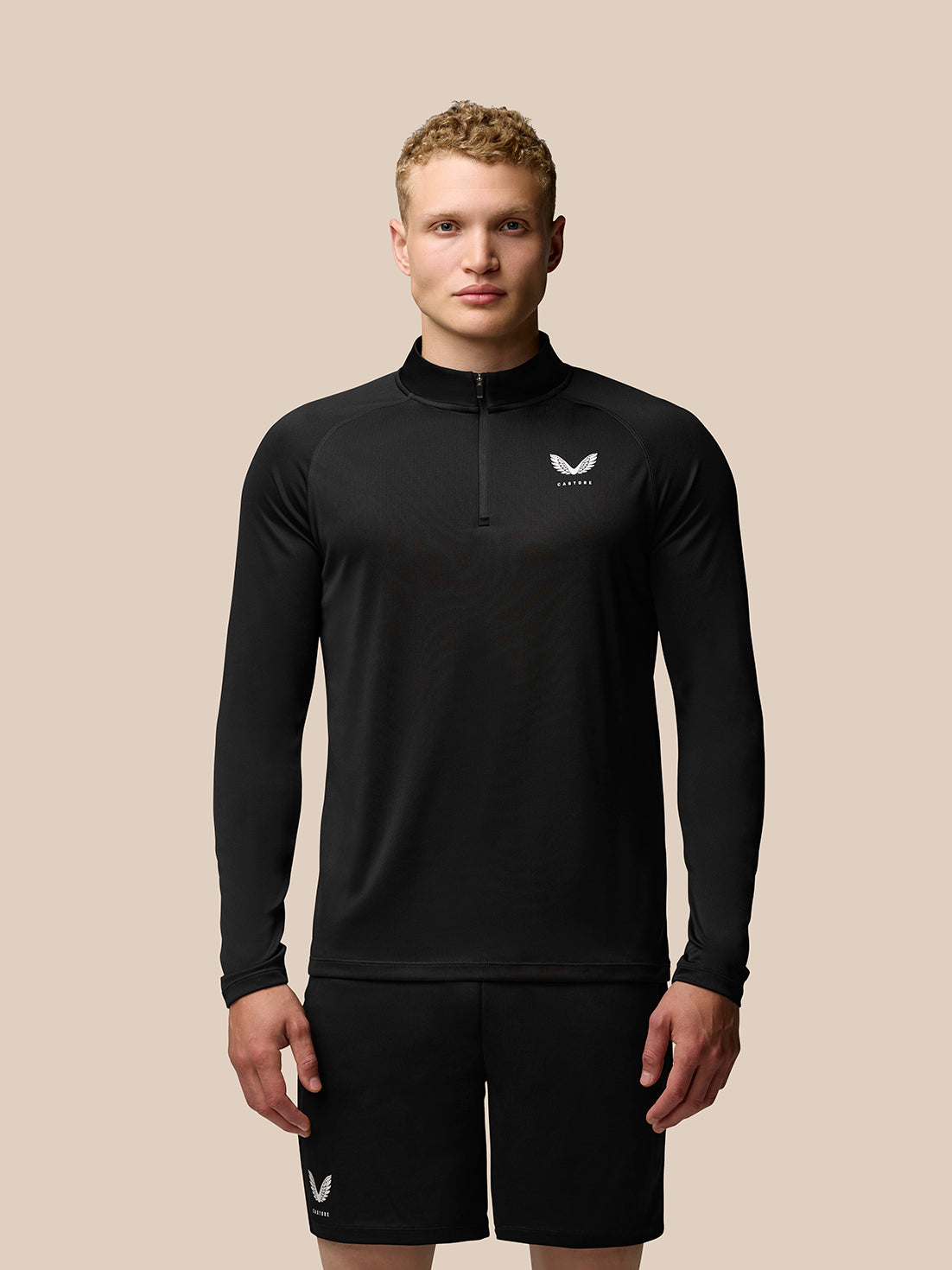 Front view of a man wearing Adapt Training quarter-zip top in black with stand collar and Castore logo on the left chest