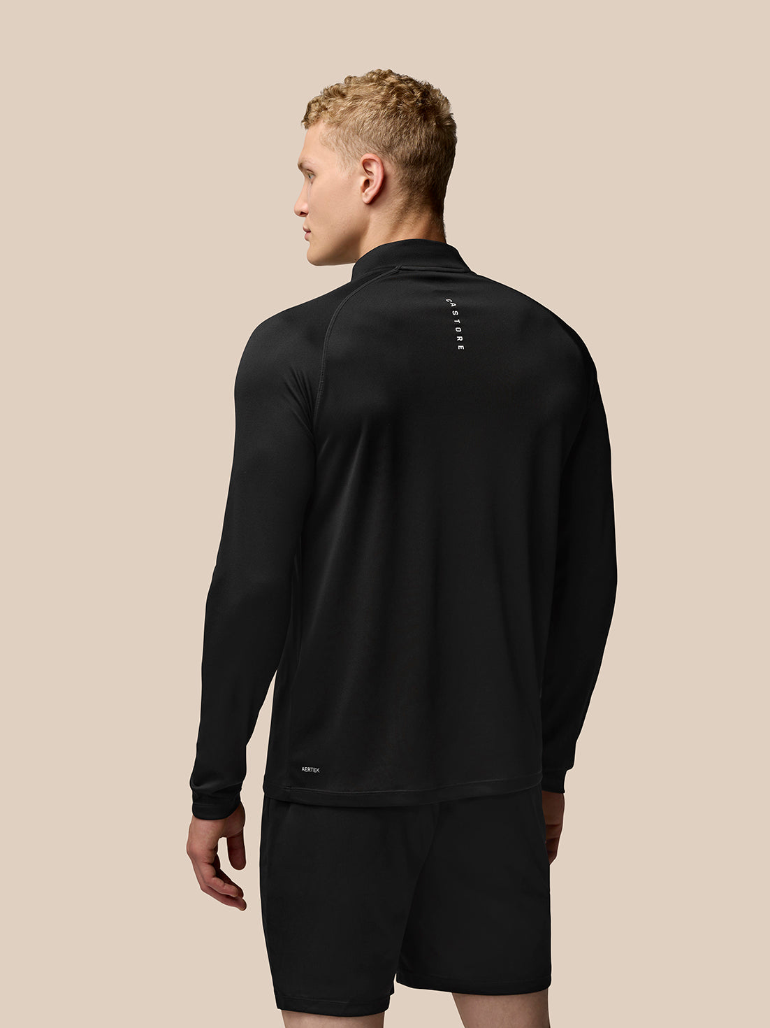 Back view of man wearing Adapt Training quarter-zip top in black with branding visible at the upper back