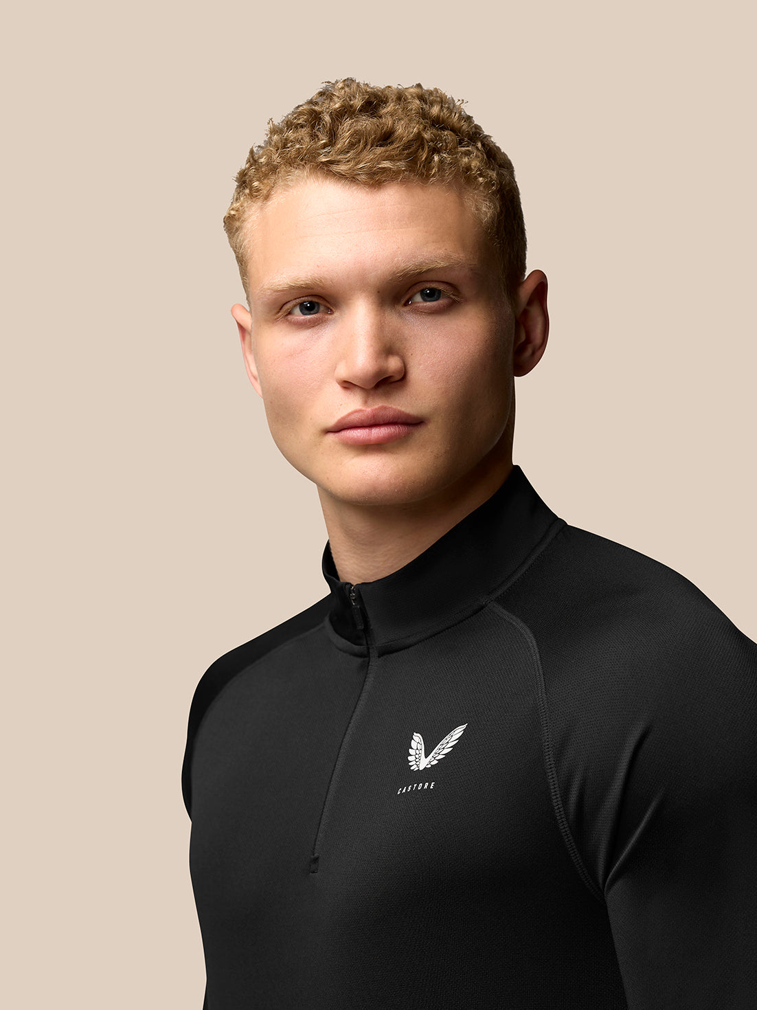 Male model wearing black Adapt Training 1/4 Zip Top with stand collar and Castore logos on chest and upper back