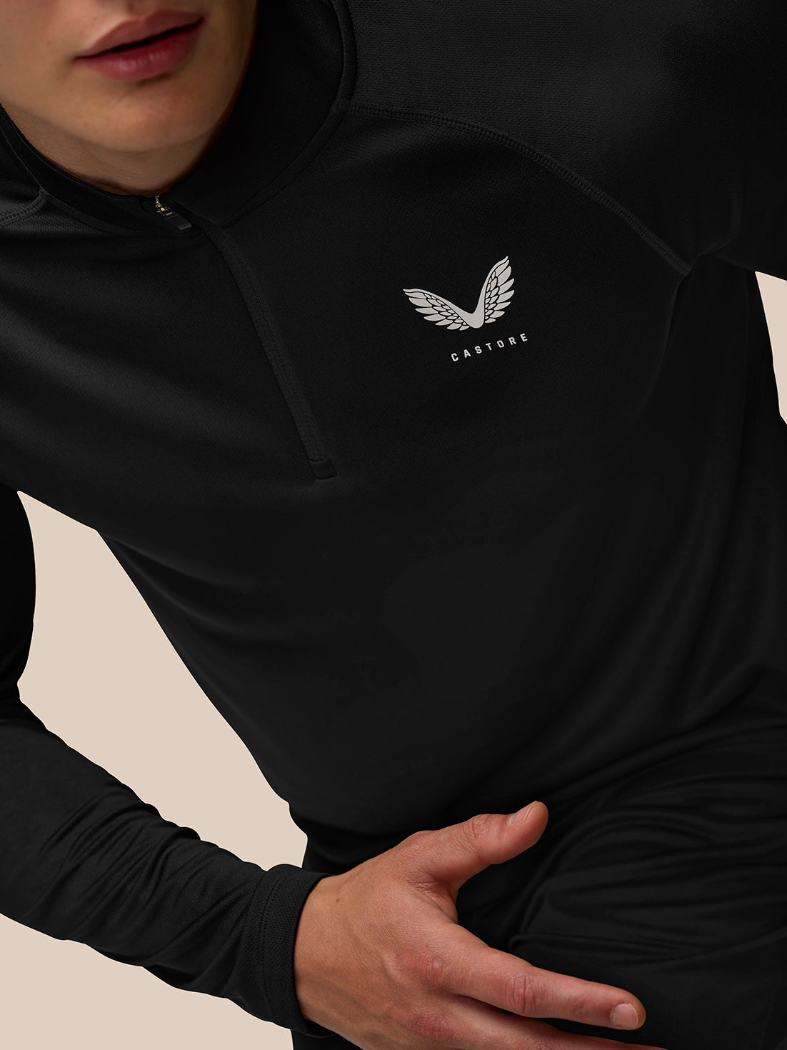 Close-up of chest area on black Adapt Training top showing Castore logo and zip detail
