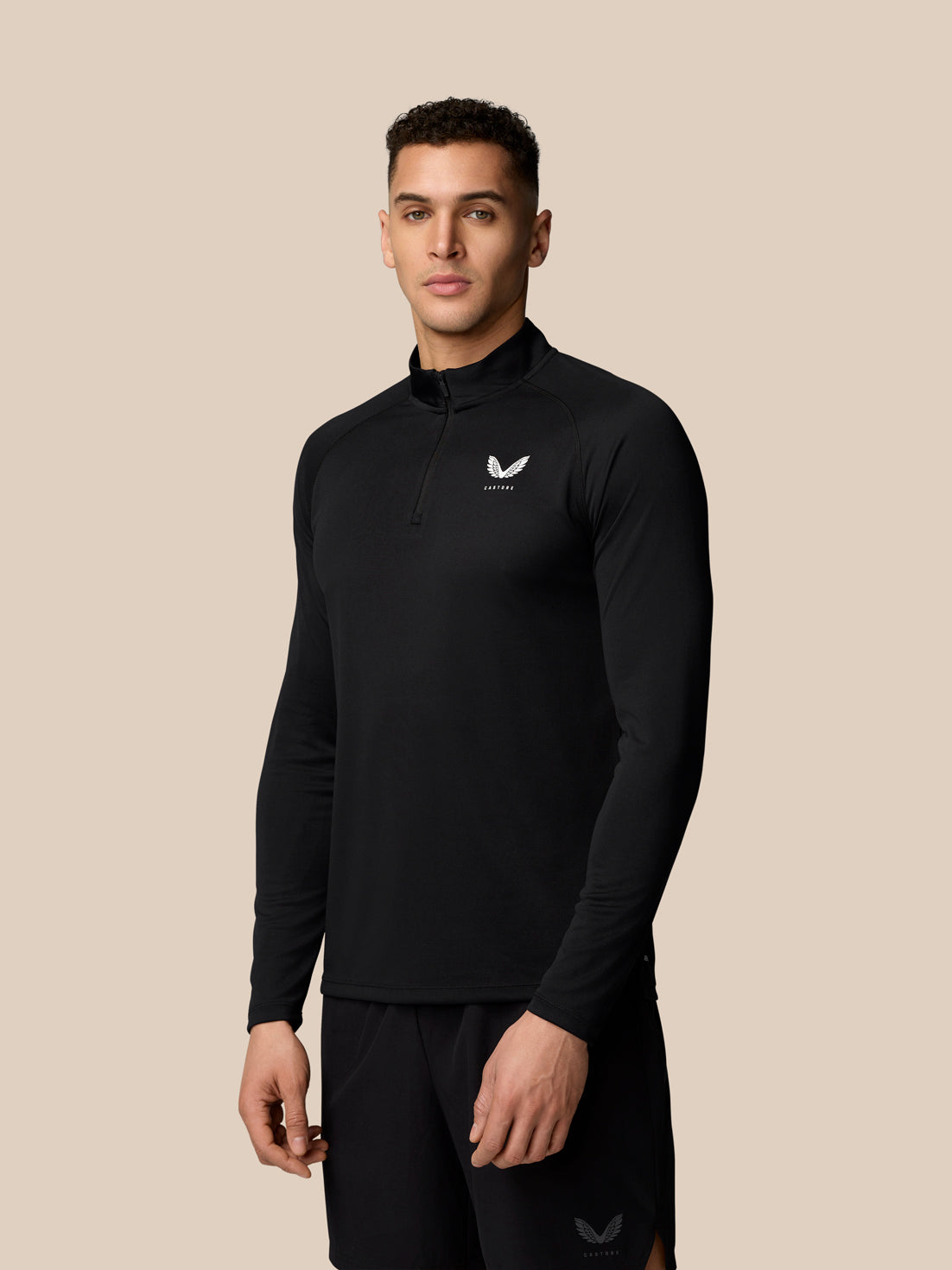 Male model wearing black Adapt Training 1/4 Zip Top with white Castore logo on chest