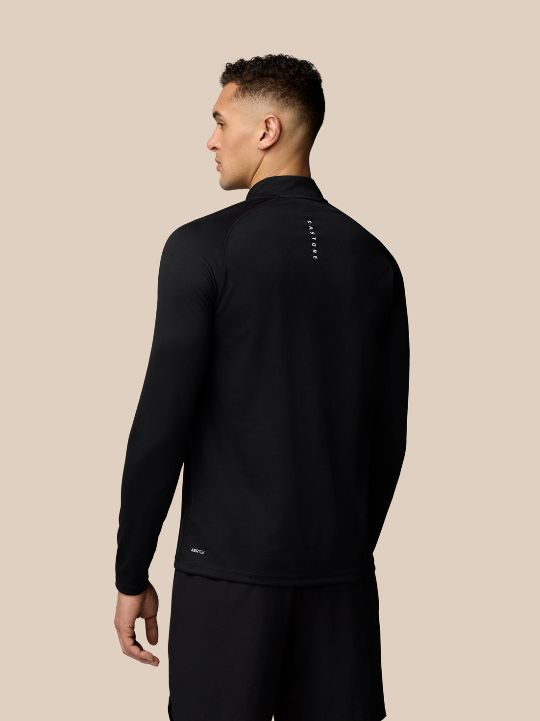 Back view of a man wearing a black Adapt Training 1/4 Zip Top with Castore branding along the upper back