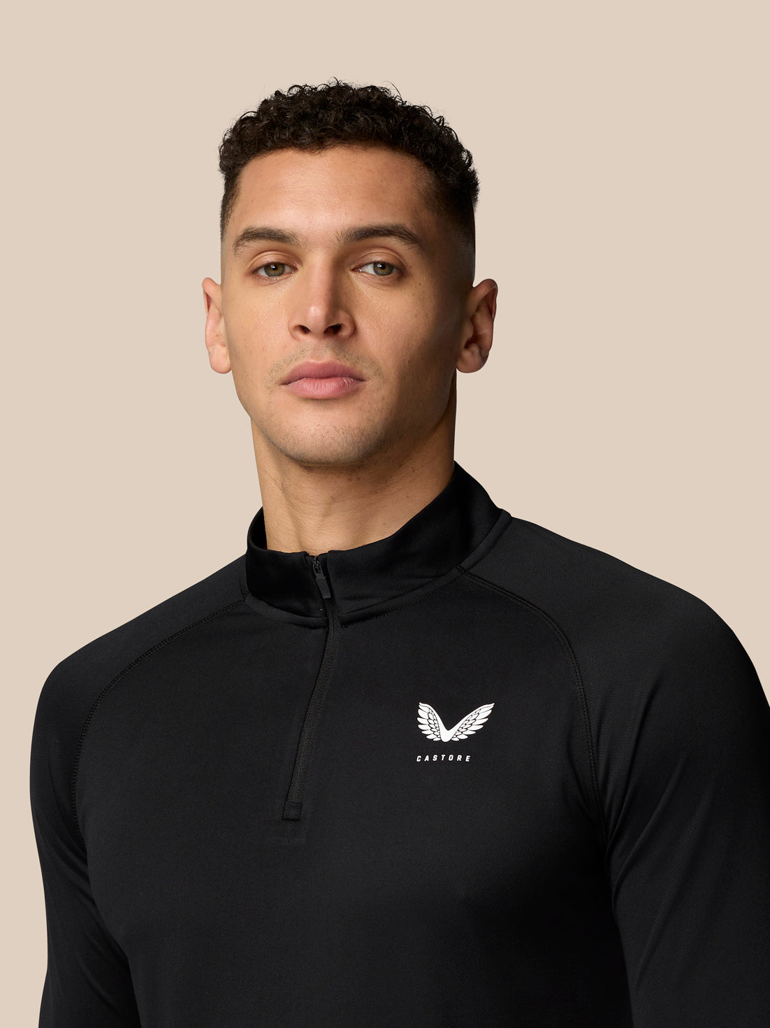 Front view of a man in a black Adapt Training 1/4 Zip Top with quarter zip and Castore logo on the chest