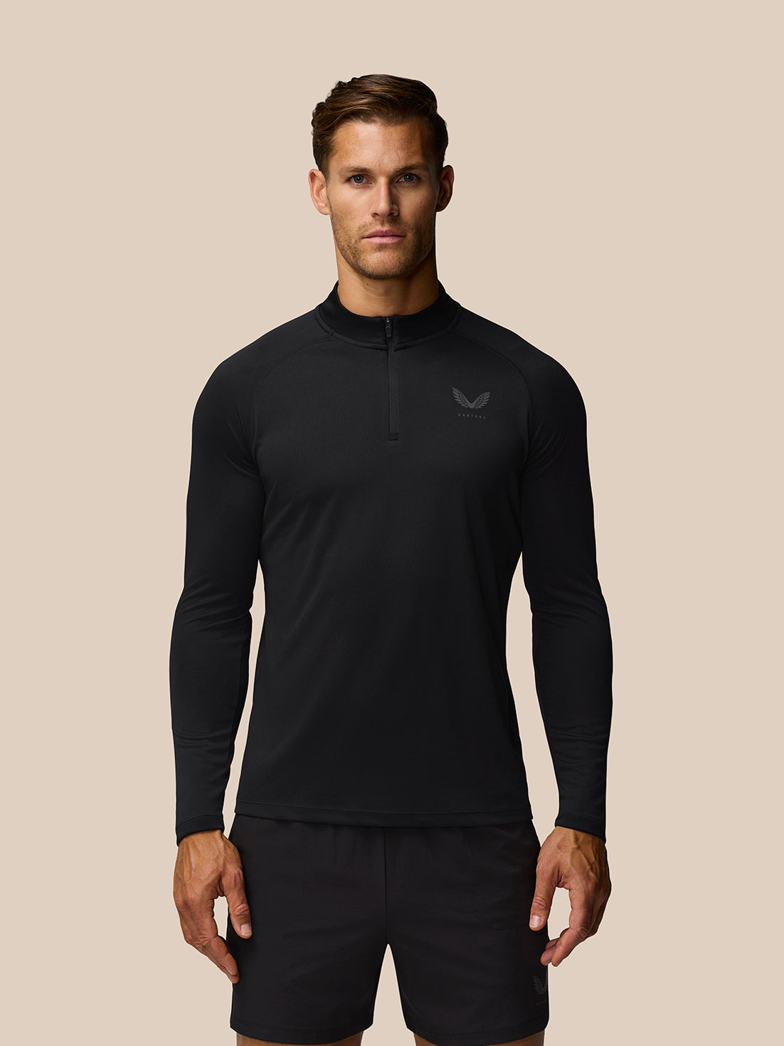 Male model wearing black Adapt Training 1/4 Zip Top with front quarter zip and left chest logo.