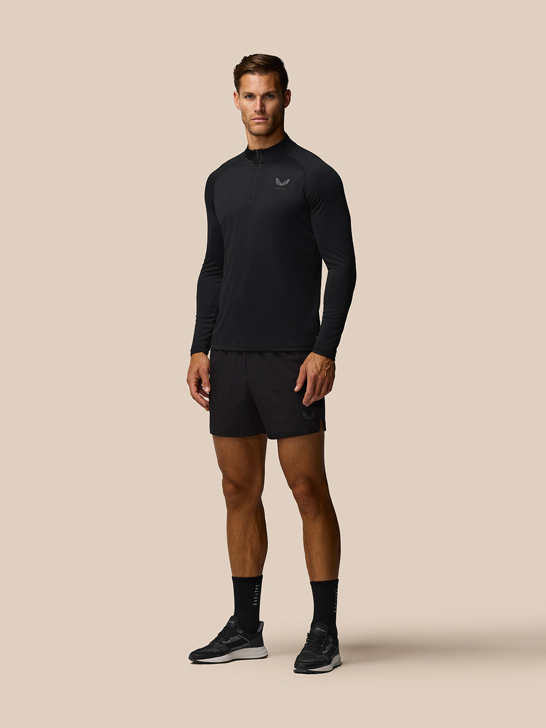 Male model wearing black Adapt Training 1/4 Zip Top with front quarter zip and left chest Castore logo
