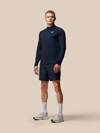Man wearing navy Adapt Training 1/4 Zip Top with stand collar and raglan sleeves, paired with navy shorts