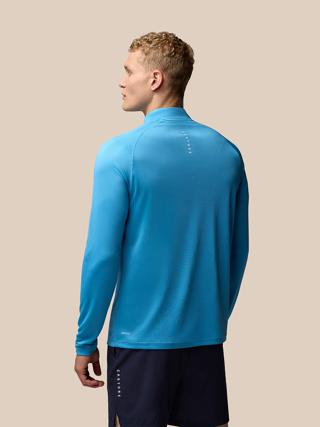 Back view of a man wearing corn blue Adapt Training 1/4 Zip Top showing upper back branding