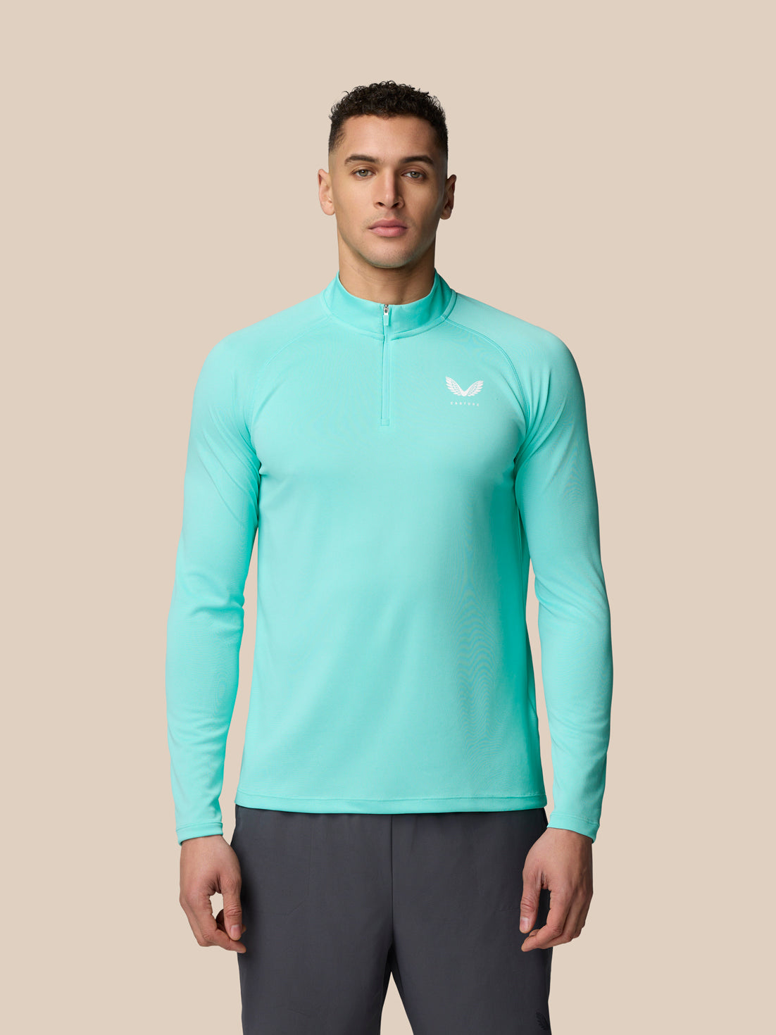 Man wearing a light aqua Adapt Long Sleeve top with a quarter zip and Castore branding on the chest.