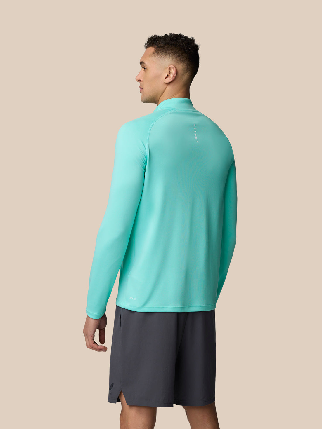 Back view of a man in light aqua Adapt Training 1/4 Zip Top with raglan sleeves and Castore branding on the upper back