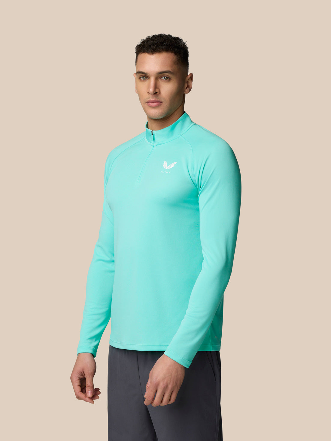 Three-quarter front view of a man wearing light aqua Adapt Training 1/4 Zip Top with zipper at neck and Castore logo on left chest