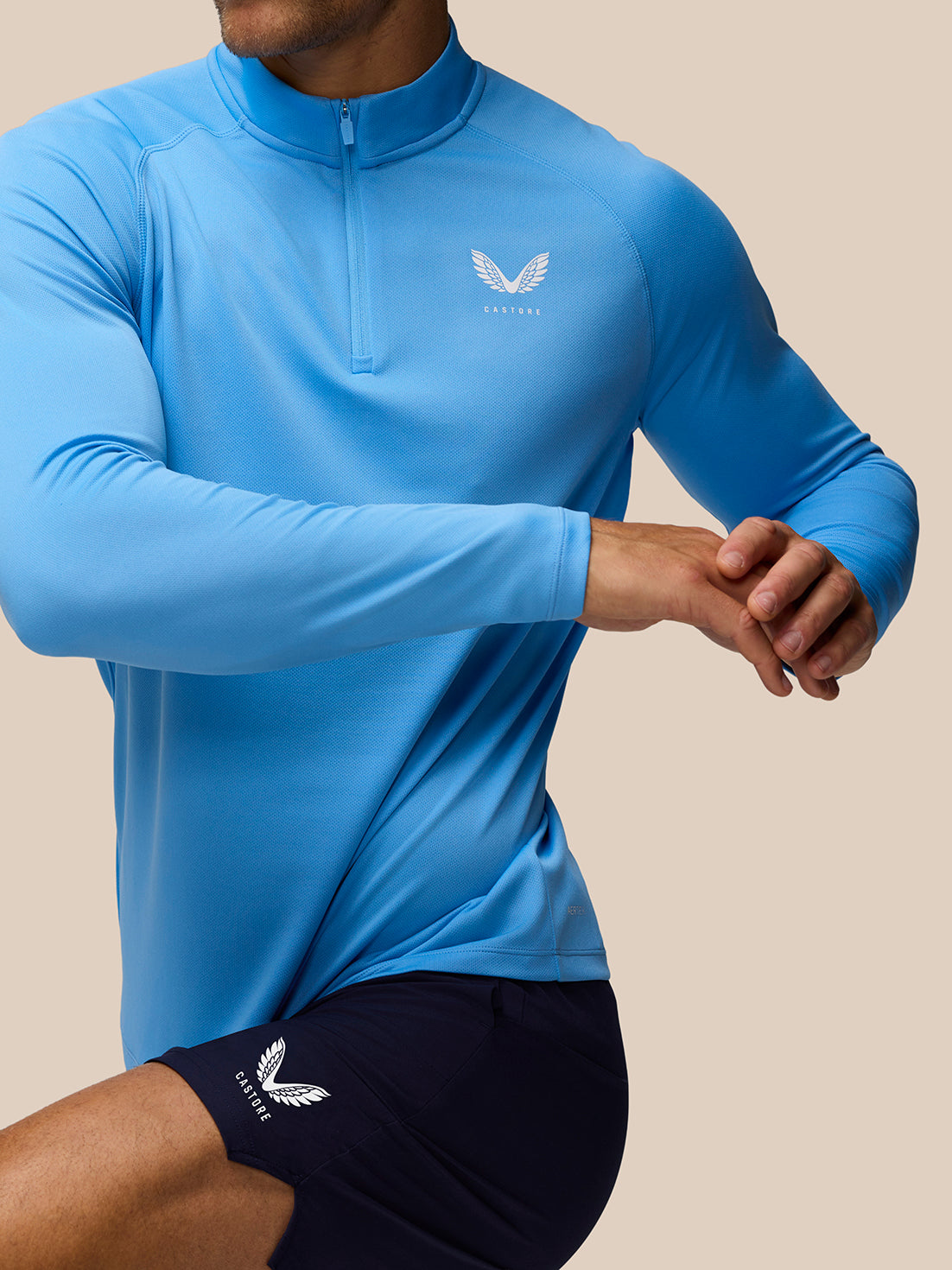 Man wearing blue Adapt Training 1/4 Zip top with center zip and raglan shoulders.