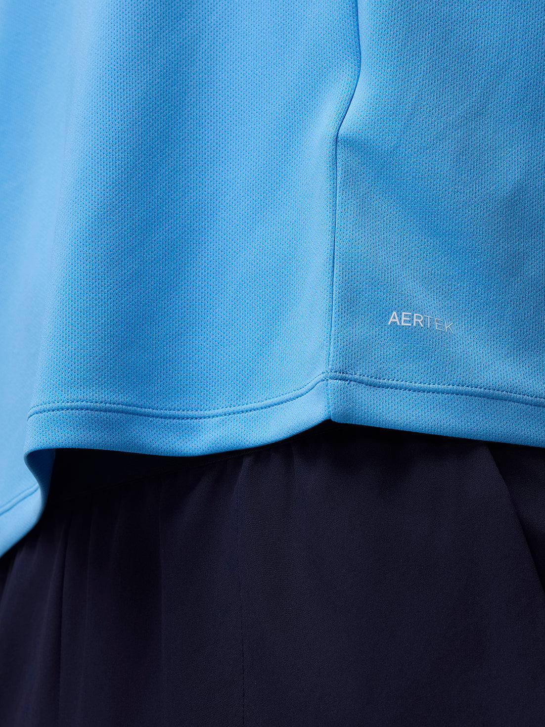 Close-up of the blue Adapt Training top hem featuring the AerTek logo.