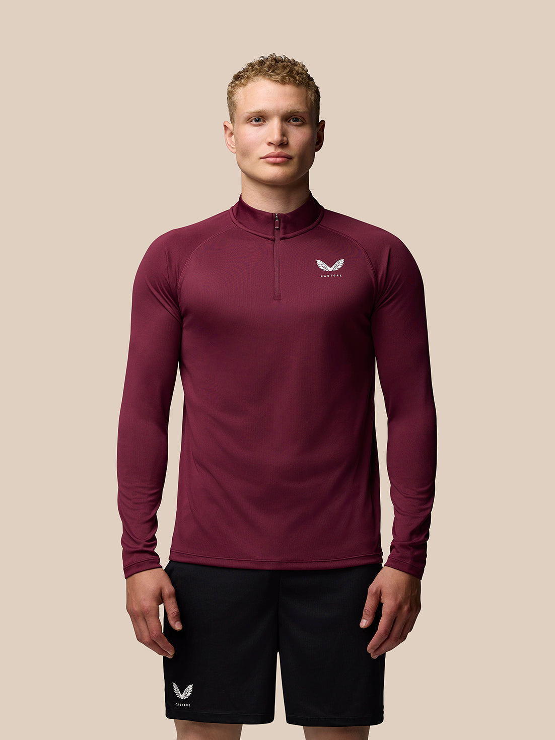 Male model wearing burgundy Adapt Training long sleeve quarter zip top with stand collar and logo on chest