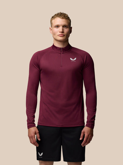Male model wearing burgundy Adapt Training long sleeve quarter zip top with stand collar and logo on chest