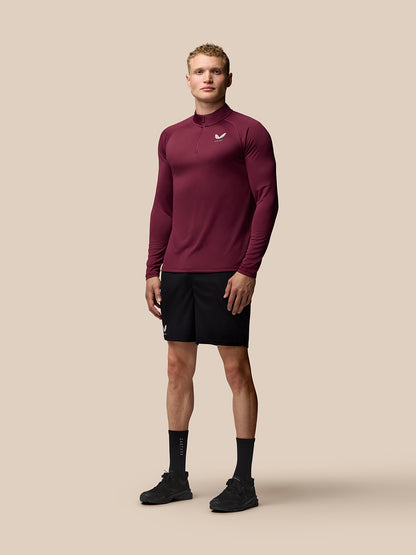 Man wears burgundy Adapt Training 1/4 Zip Top with stand collar and raglan sleeves