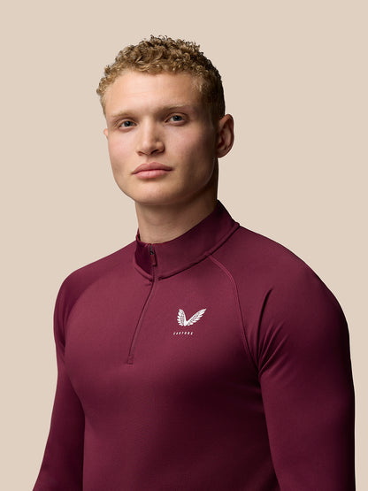 Portrait of a model wearing burgundy Adapt Training top with Castore crest on the left chest