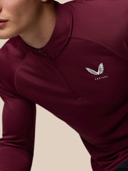Close up of burgundy Adapt Training top showing a white Castore wing logo on the left chest