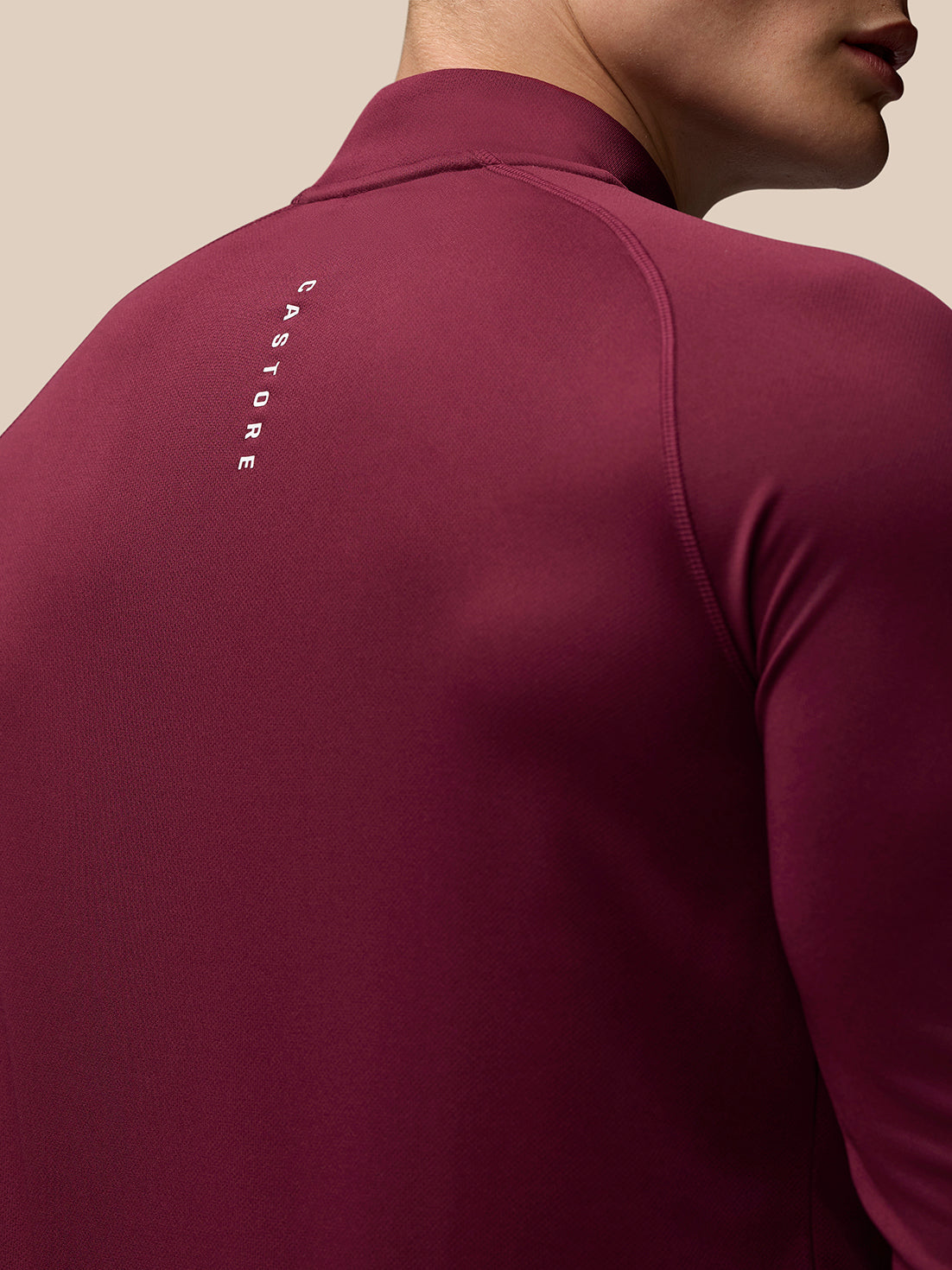 Back view of burgundy Adapt Training top with vertical CASTORE branding along the upper back